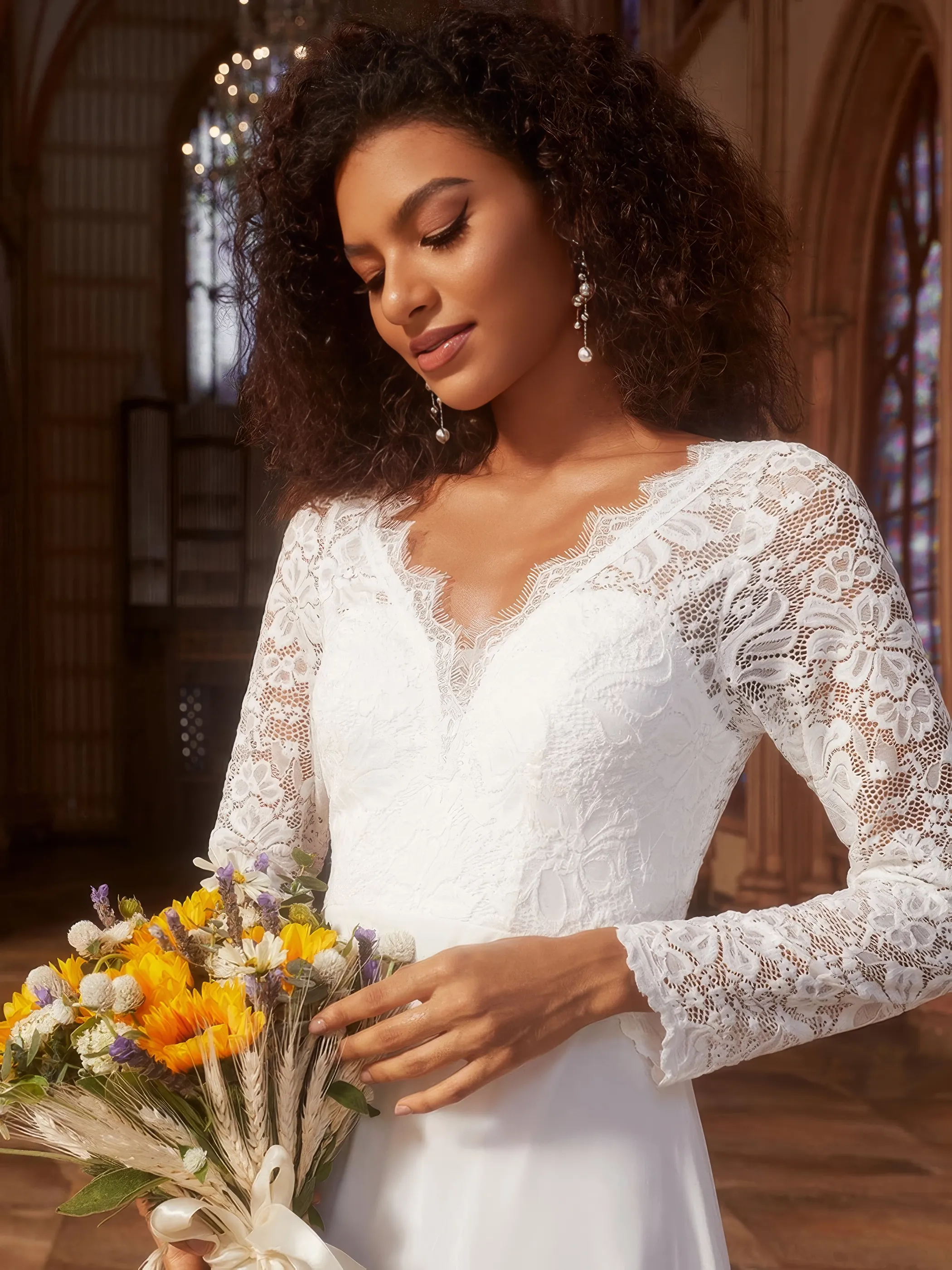 Brautkleid aus Spizte mit langen Ärmeln und V Ausschnitt, Close-up Dunkelhäutige Braut in einem elfenbeinfarbigen Brautkleid aus Spitze und mit langen Ärmeln, Close-up
