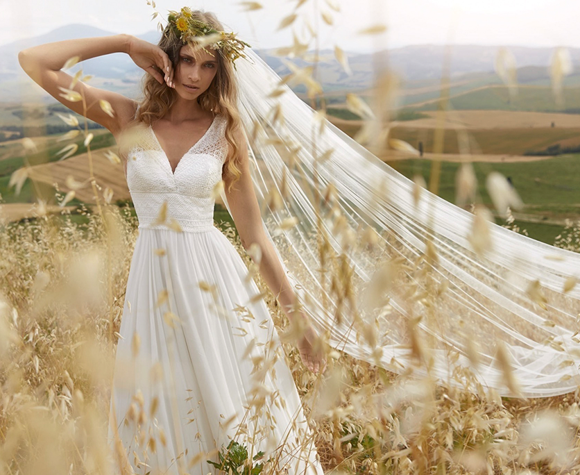 Traumkleider kauft die Braut bei Samyra-Fashion Zürich Braut in einem schlichten Hochzeitskleid mit Schleier im Kornfeld