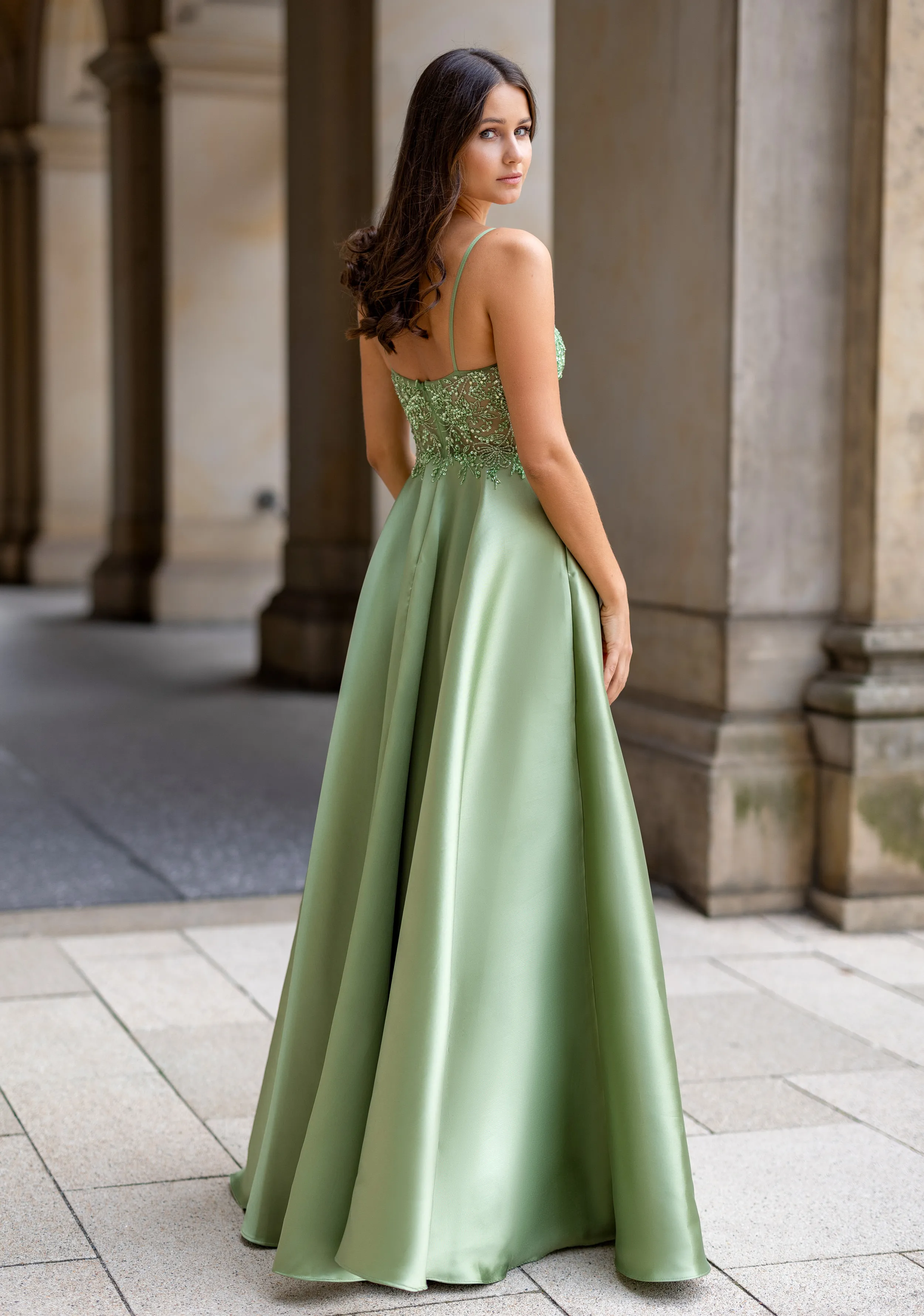 Frau in einem grünen Ballkleid aus Mikado-Stoff und mit Taschen, Rückenansicht