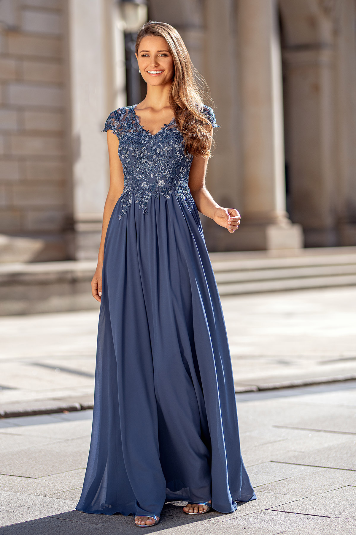 Frau in einem blauen langen Abendkleid mit Schulterärmeln