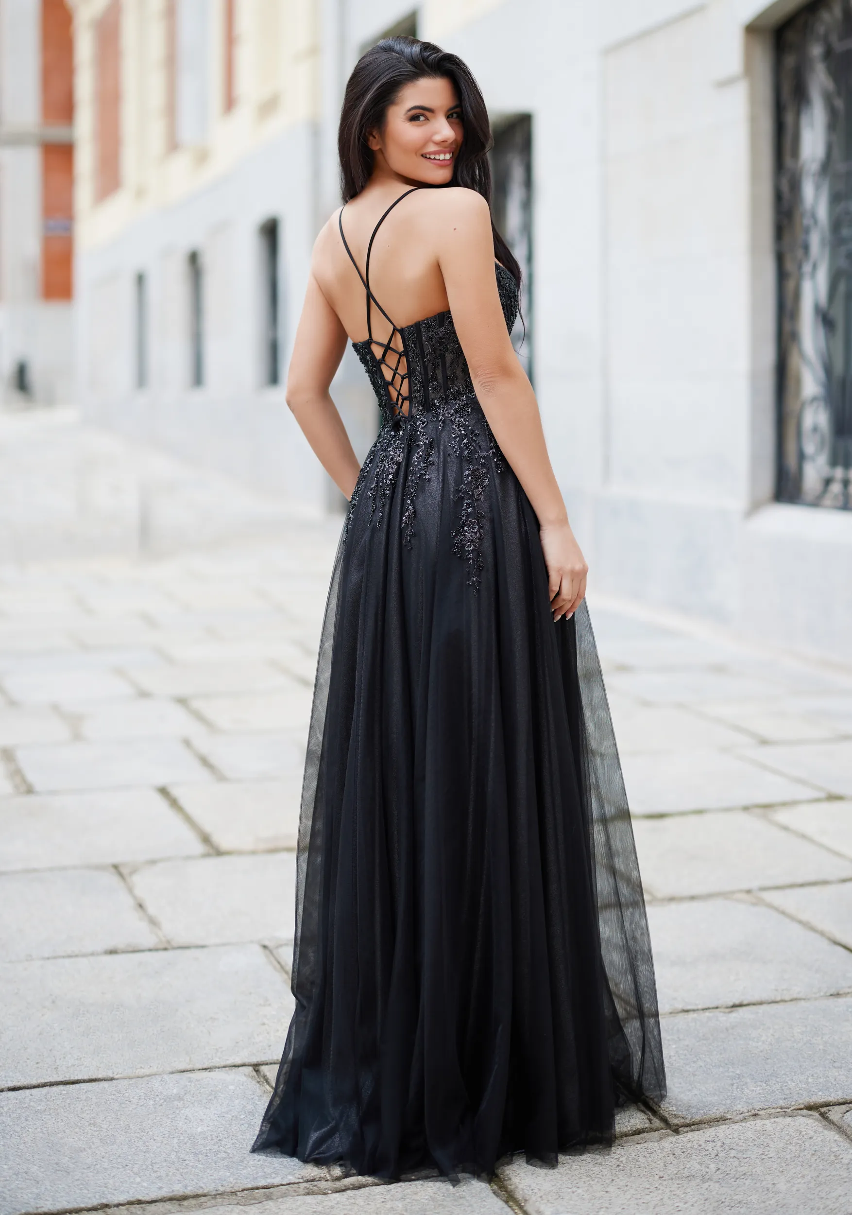 Frau in einem schwarzen Ballkleid mit Korsage und Beinschlitz, Rückenansicht