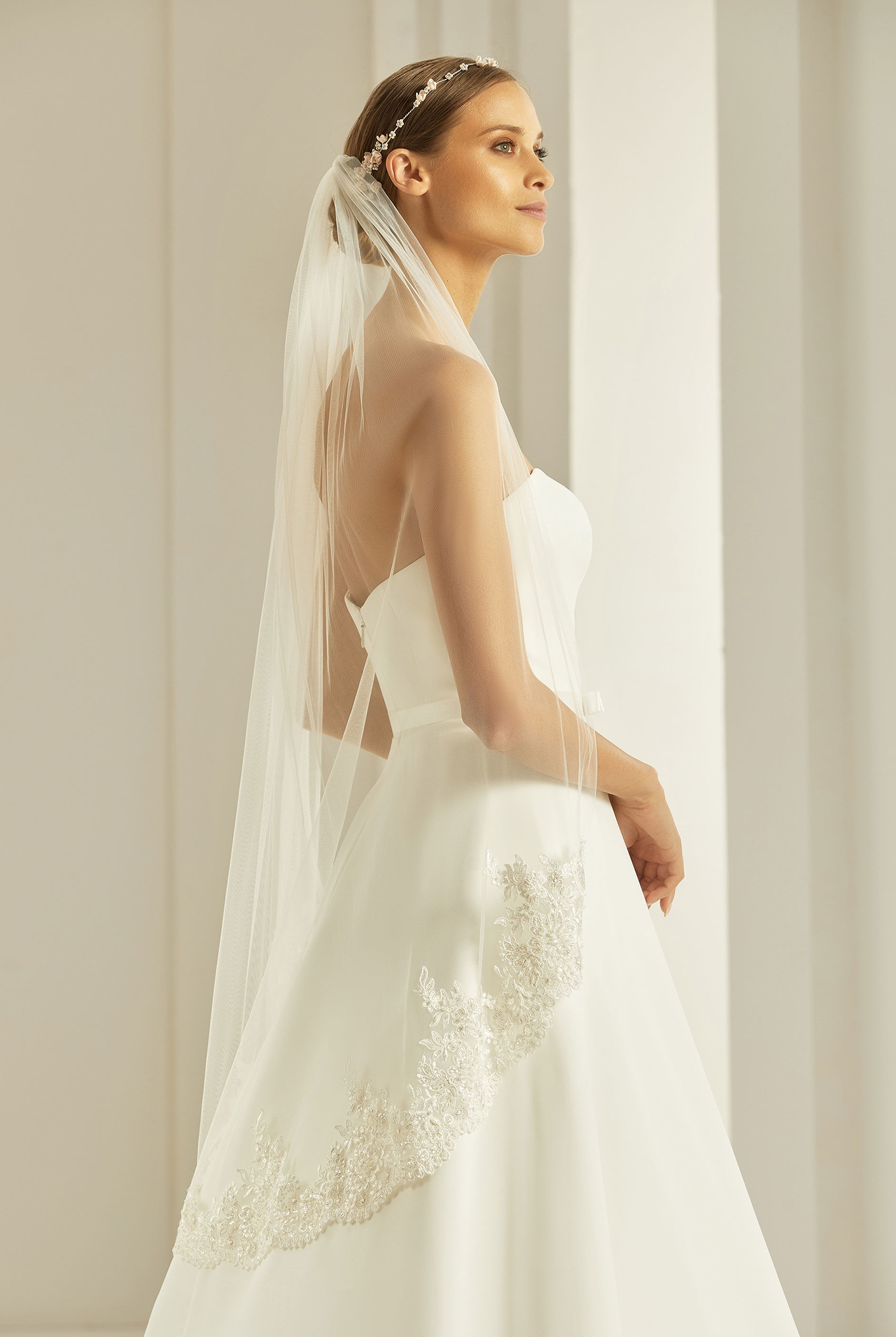Braut in einem schlichten Brautkleid kombiniert mit einem Brautschleier mit Spitzenrand