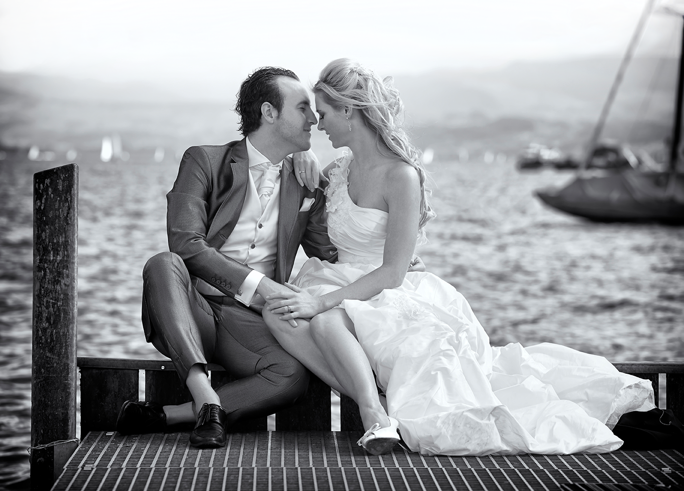 Brautpaar sitzt verliebt am Schiffssteg am See
