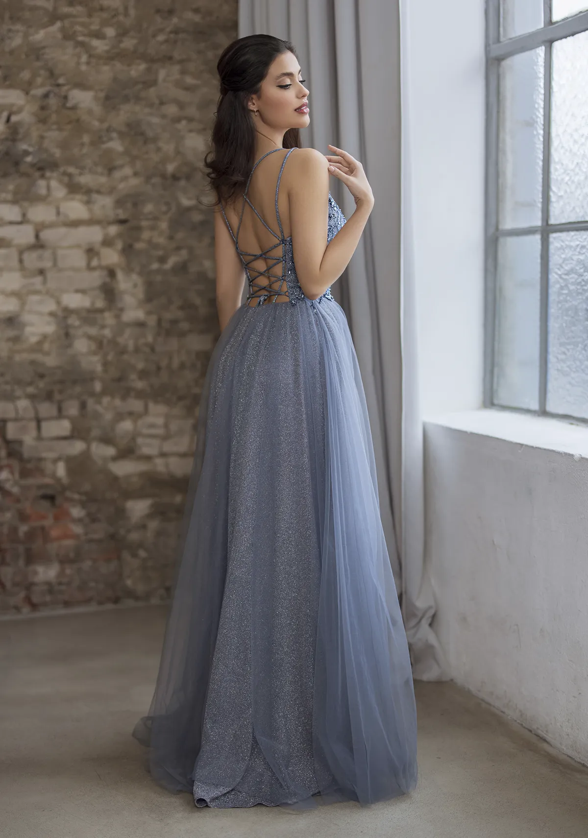 Frau in einem Ballkleid aus Tüll und Glitzerstoff und mit Beinschlitz Rauchblau, Rückenansicht