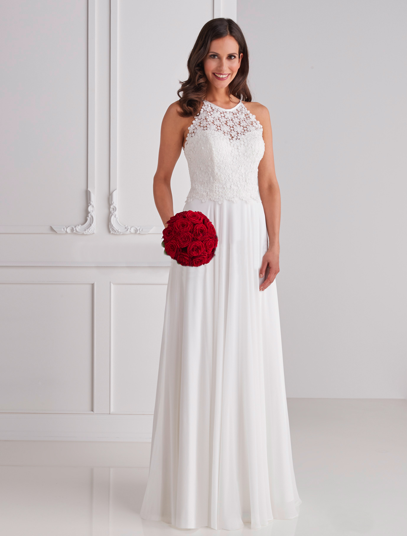Chiffon-Hochzeitskleid Heleni elfenbeinfarben mit Spitzenoberteil zu kaufen bei-Samyra Fashion-Zürich Braut in einem hochgeschlossenen, schlichten Brautkleid hält einen roten Brautstrauss in der Hand
