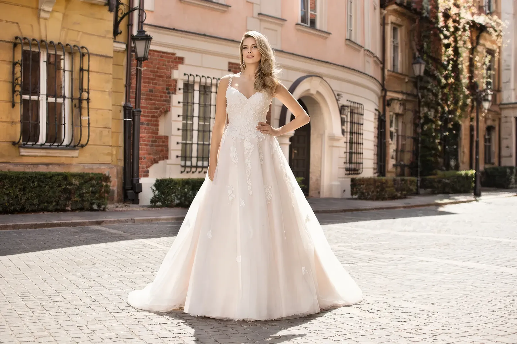 Braut im Brautkleid mit zarten rosa Blütenapplikationen und A-Linien-Schnitt in urbanem Stadtbild