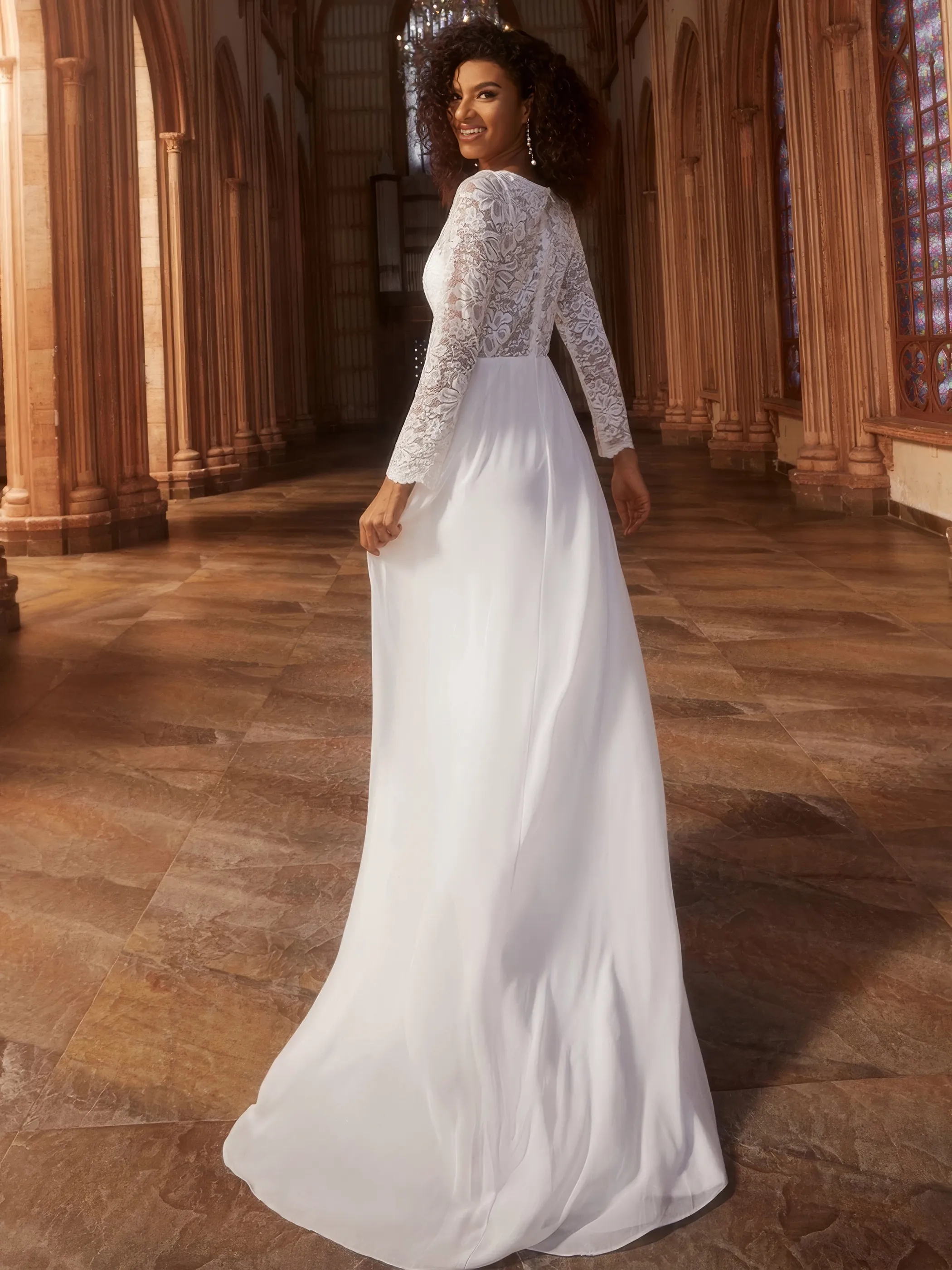 Dunkelhäutige Braut in einem elfenbeinfarbigen Brautkleid aus Spitze und mit langen Ärmeln, Rückenansicht