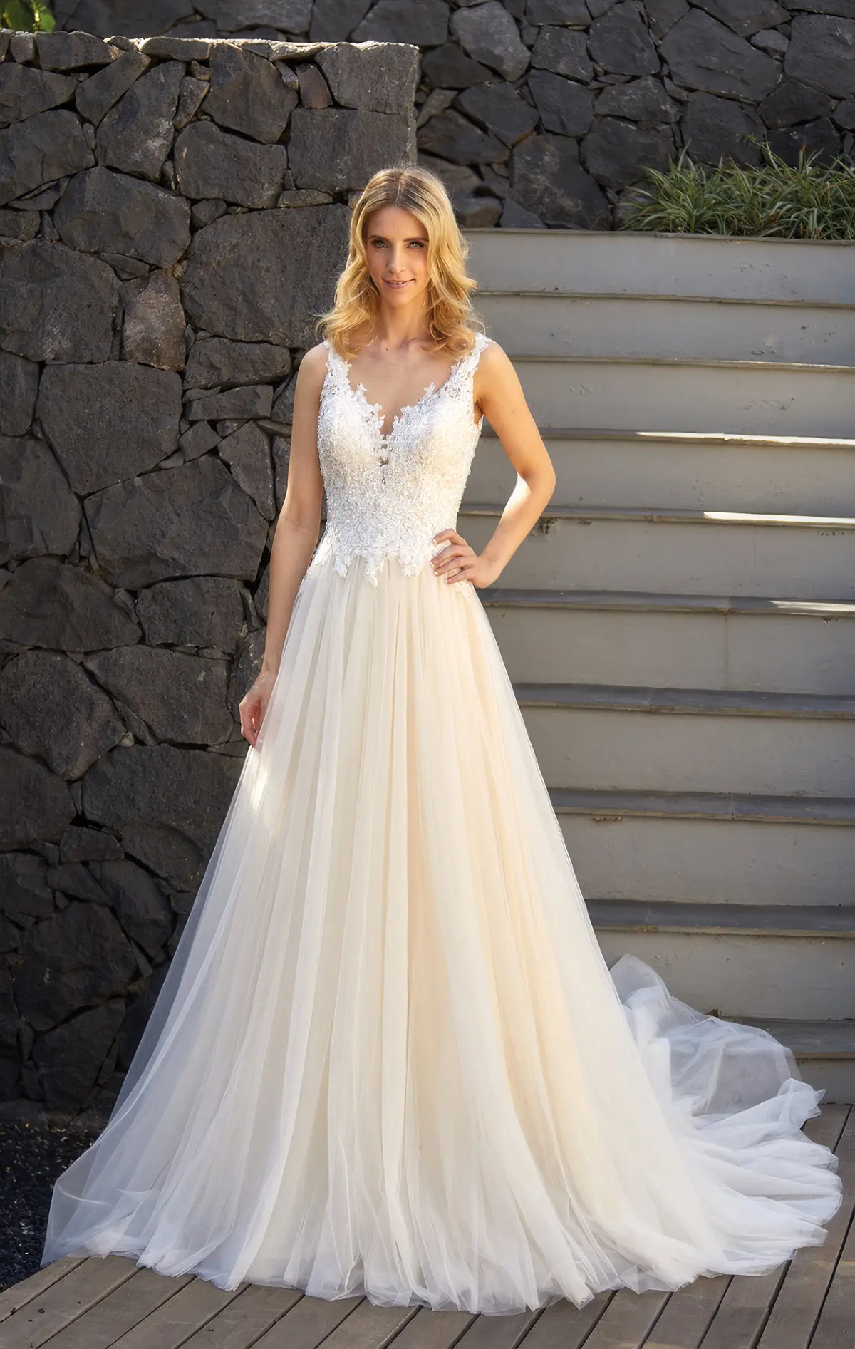 Brautkleid Davina in A-Linie und mit Tüll, Einzelstück in der Grösse 42 Frau in einem Tüll-Brautkleid mit Spitzenoberteil vor einer Treppe