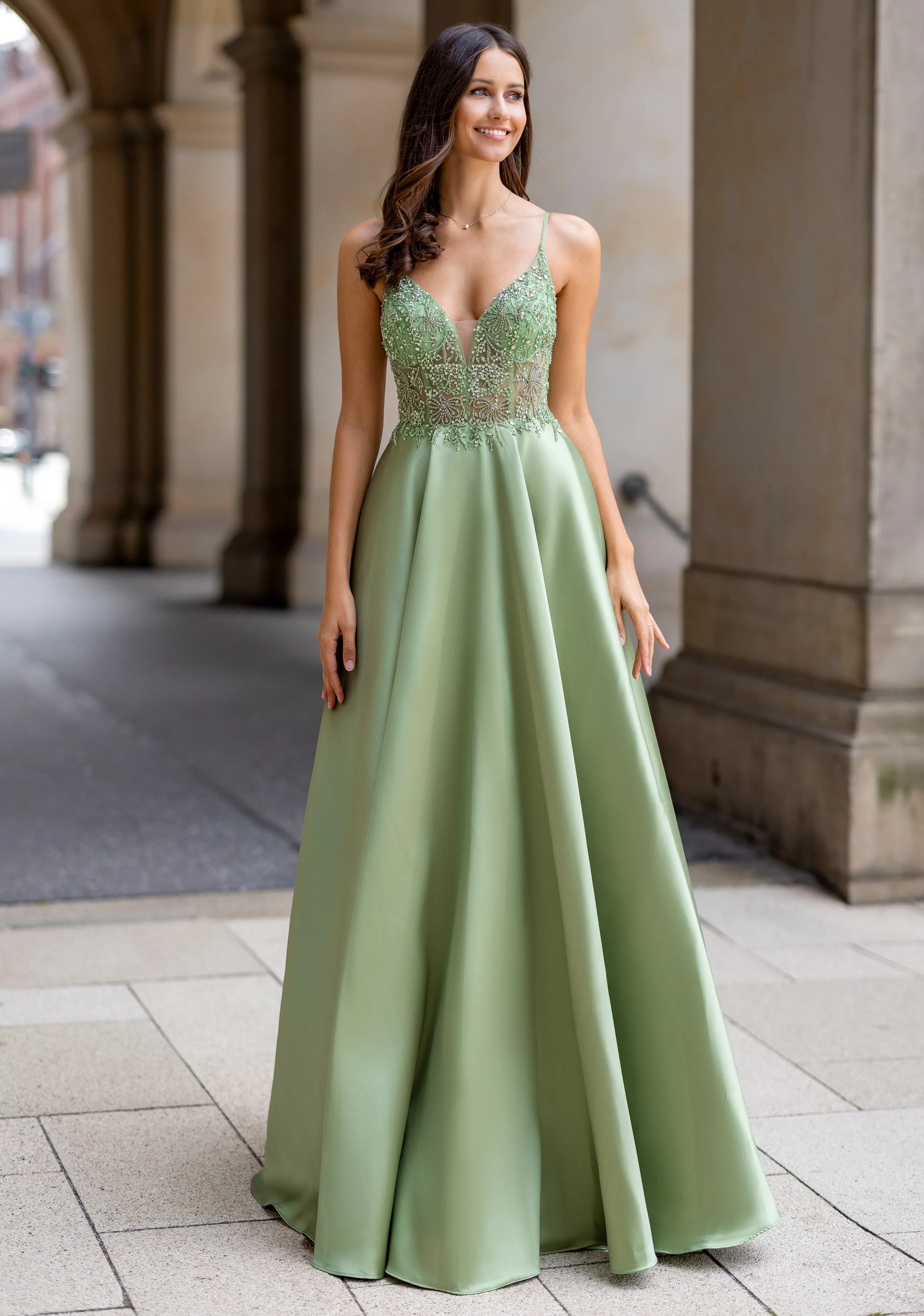 Frau in einem grünen Ballkleid aus Mikado-Stoff und mit Taschen