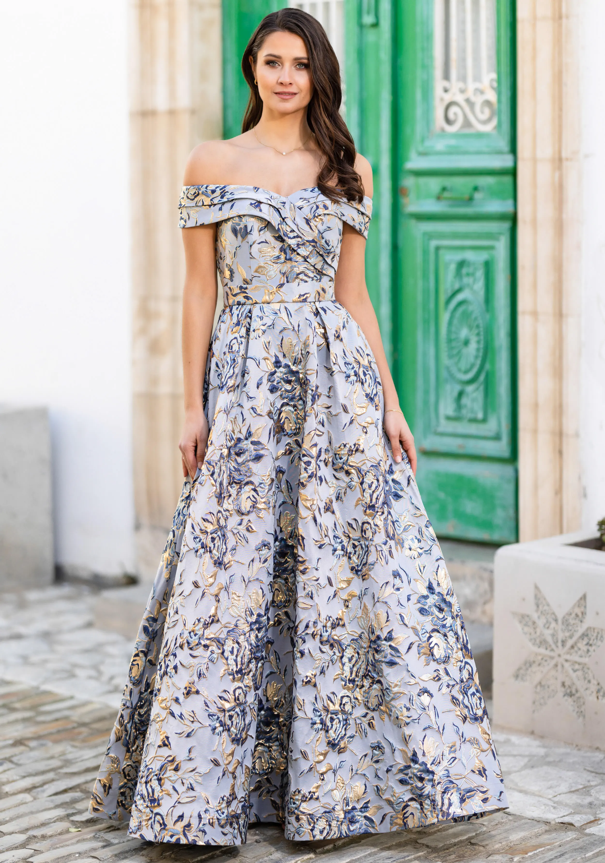 Frau in einem langen Brokat-Ballkleid mit Carmenausschnitt und Taschen