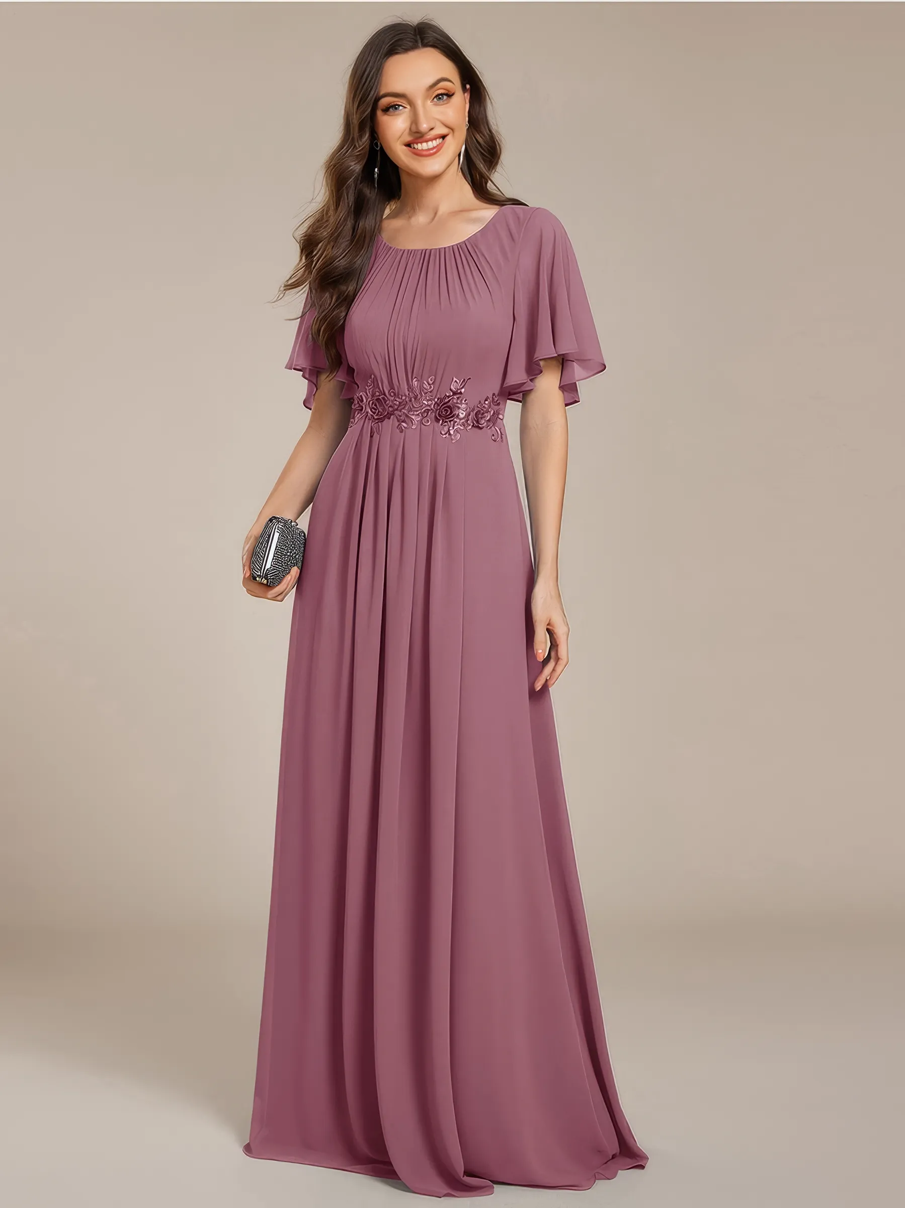 Langes Abendkleid in Mauve-Rosa aus leicht elastischem Chiffon mit Rundhalsausschnitt, Fledermausärmeln und paillettenbestickten Blumenapplikationen an der Taille – elegant für Hochzeit, Gala oder als Brautjungfer.