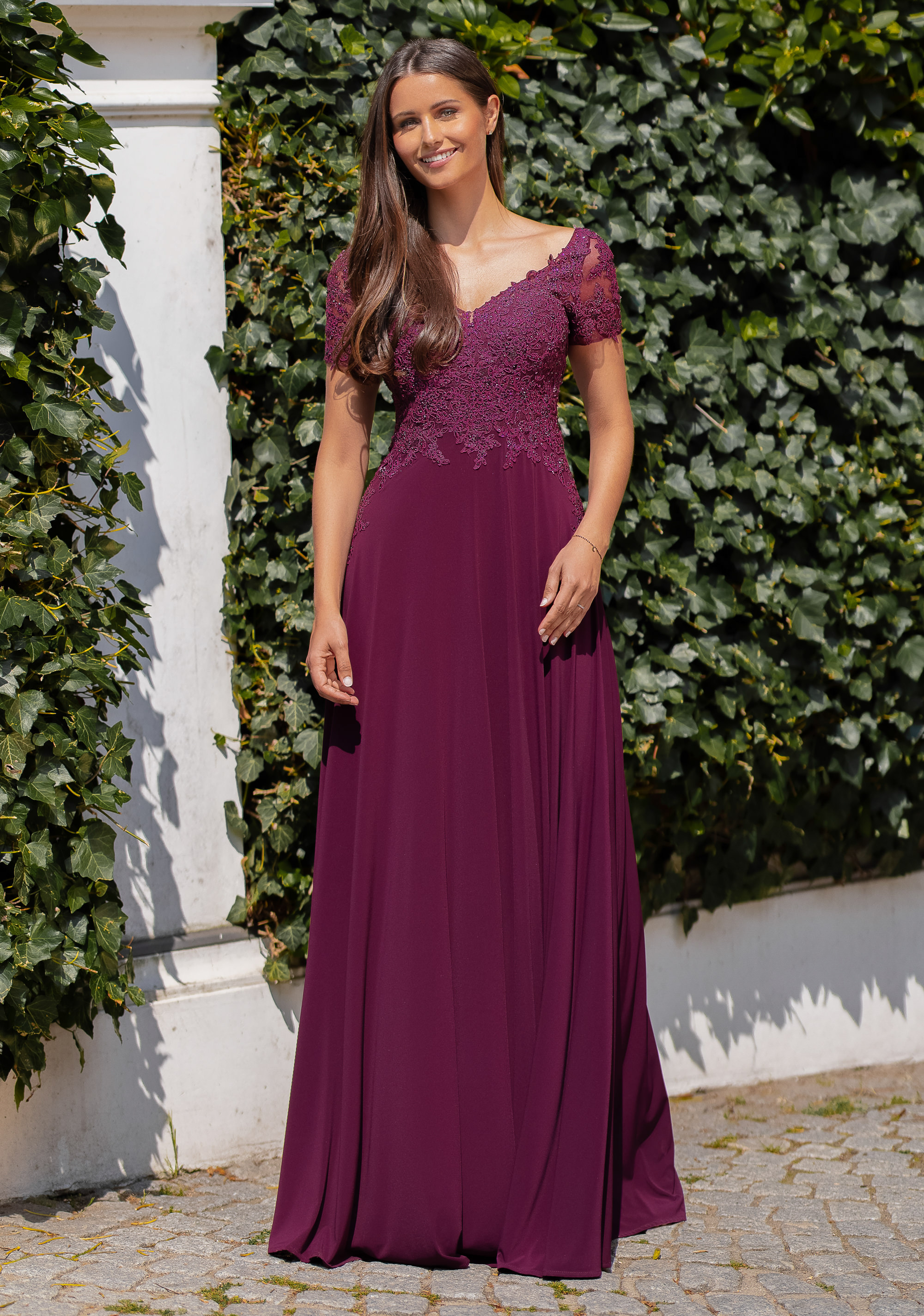 Abendkleid Cheya bordeaux mit kurzen Ärmel und V-Ausschnitt Frau in einem bordeaux-farbenen Abendkleid mit kurzen Ärmeln
