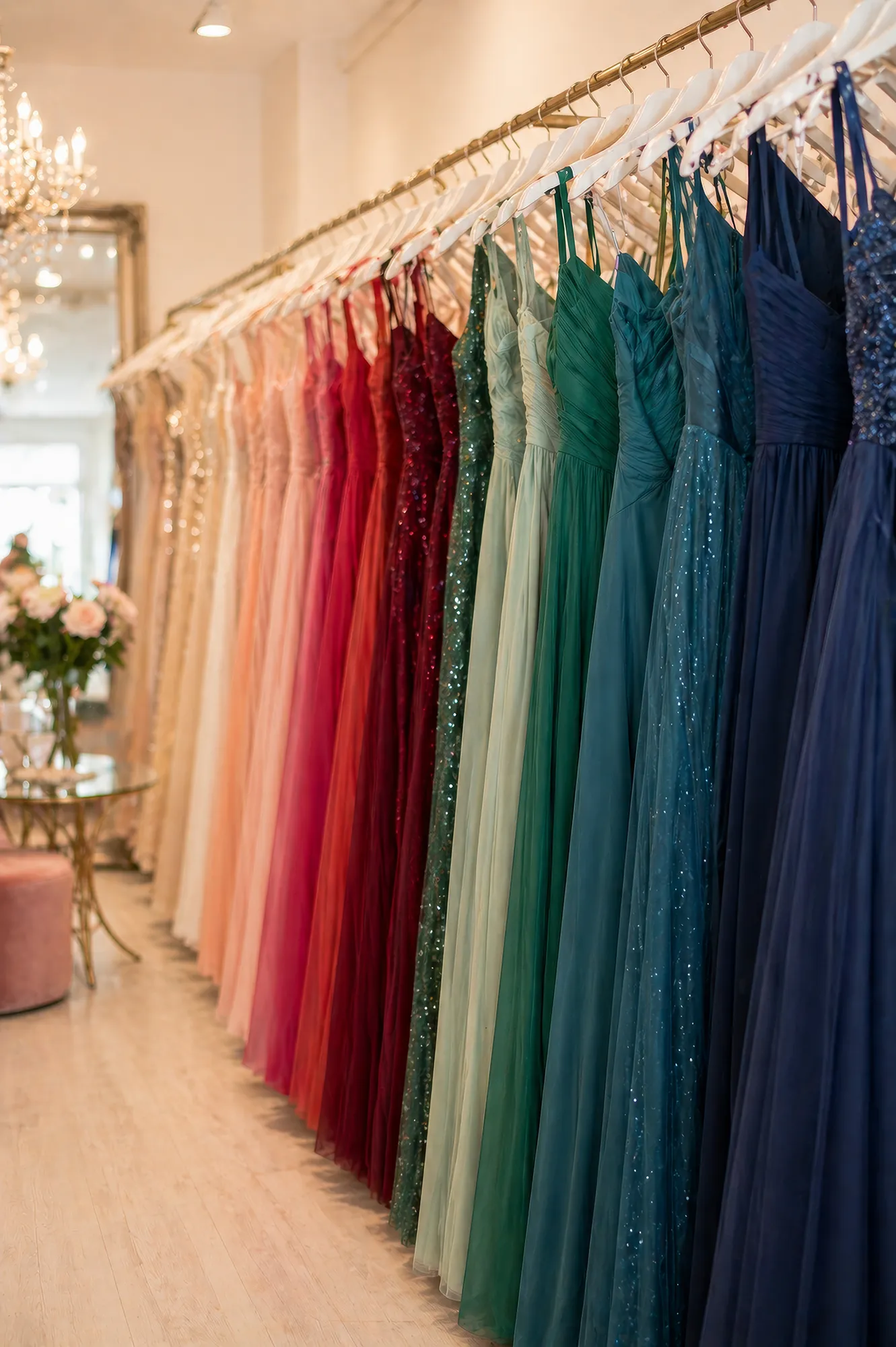 Perspektivische Aufnahme von farbig sortierten Abendkleidern auf einer Kleiderstange in einem hellen Showroom in Zürich