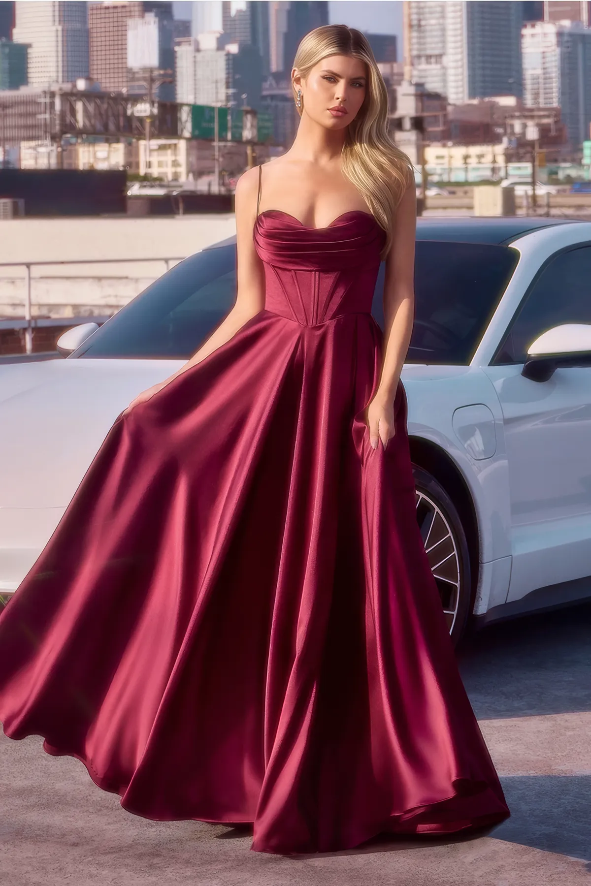 Frau in einem Bordeaux A-Linien-Abendkleid aus Satin mit Korsett-Mieder, Spaghettiträgern und Seitentaschen – eleganter Look für Galas und glamouröse Abendhochzeiten.