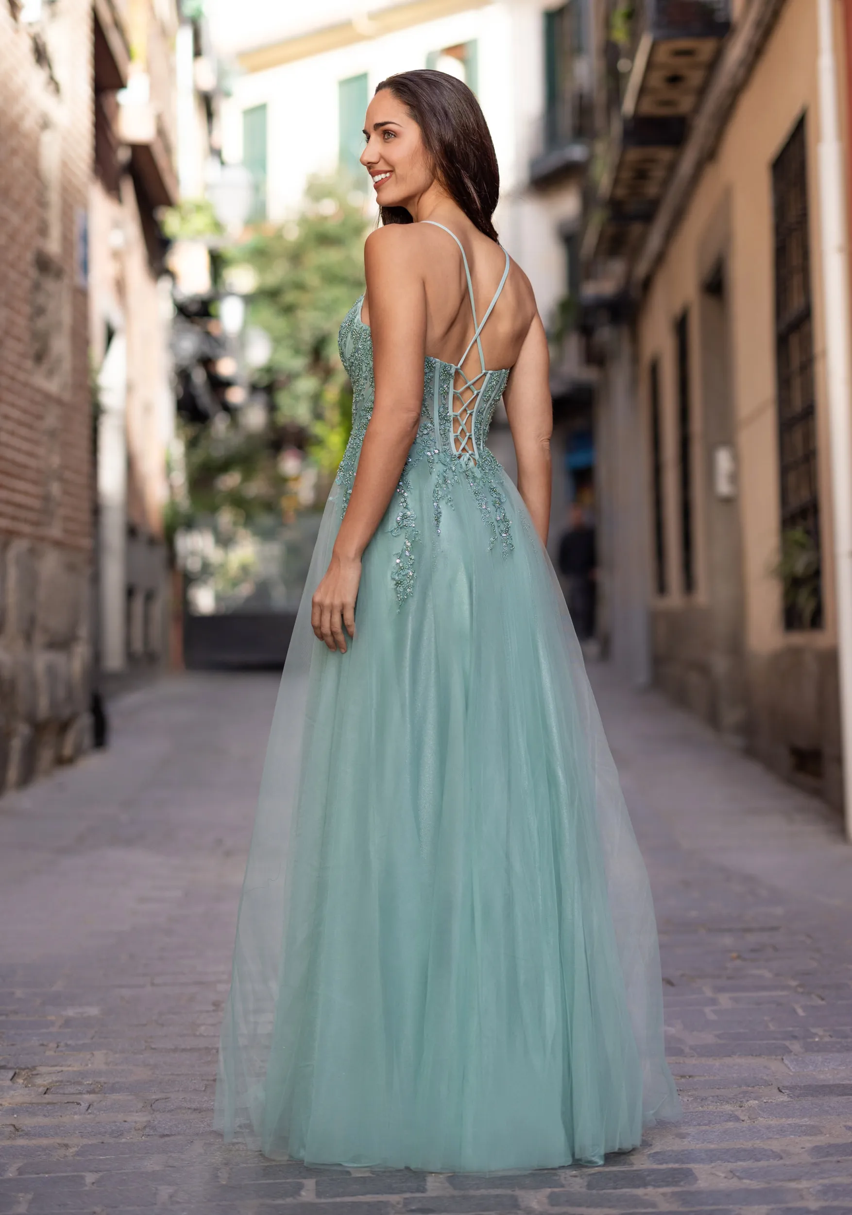 Frau in einem grünen Ballkleid mit Korsage und Beinschlitz, Rückenansicht