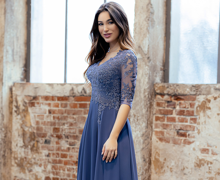 Abendkleider mit Ärmeln findest du bei Samyra Fashion Zürich Frau in einem blauen Abendkleid mit 3/4-Ärmeln