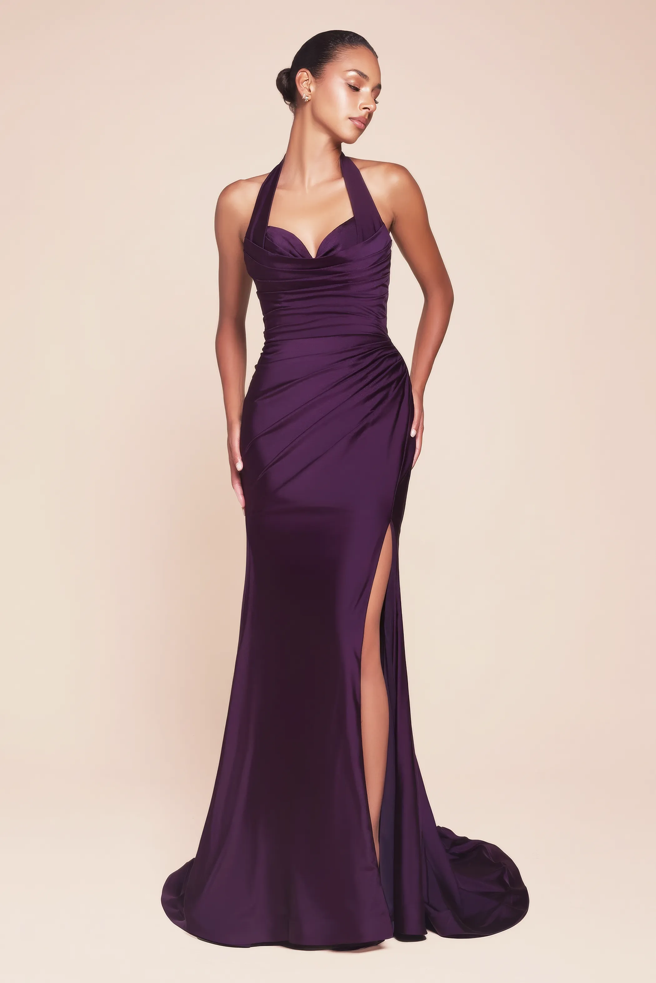 Frau in einem auberginefarbenen, figurbetonten Abendkleid mit hohem Beinschlitz