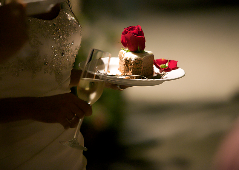 Hochzeitstorte und Champagnerglas Eine Braut hält einen Teller mit einem Stück Hochzeitstorte und ein Champagnerglas