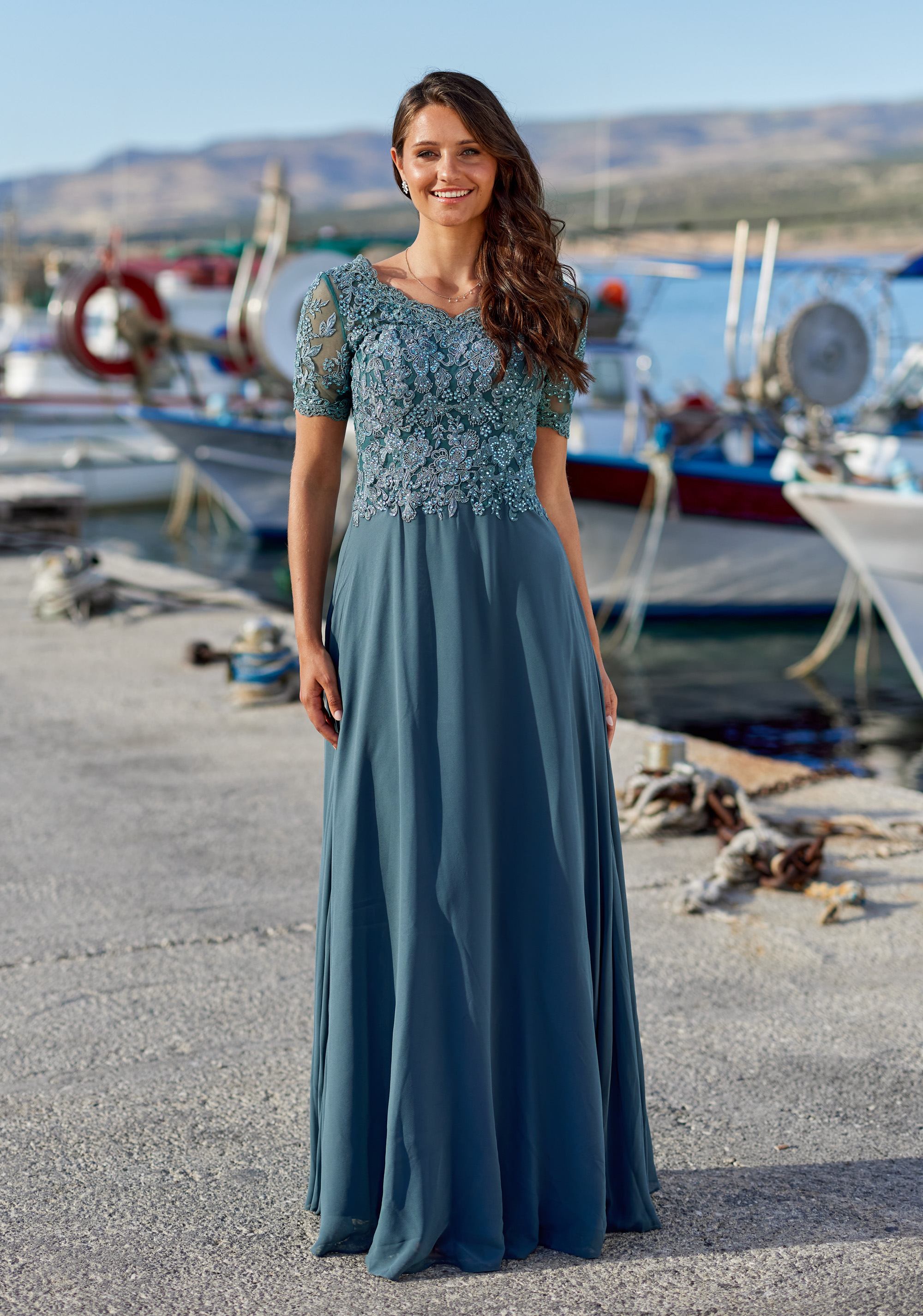 Chiffon-Abendkleid in der Farbe Moonlight Jade mit kurzen Ärmel und fliessendem Rock Frau in einem rauchblauen Chiffon-Abendkleid mit Spitzenoberteil in der Farbe Moonlight Jade
