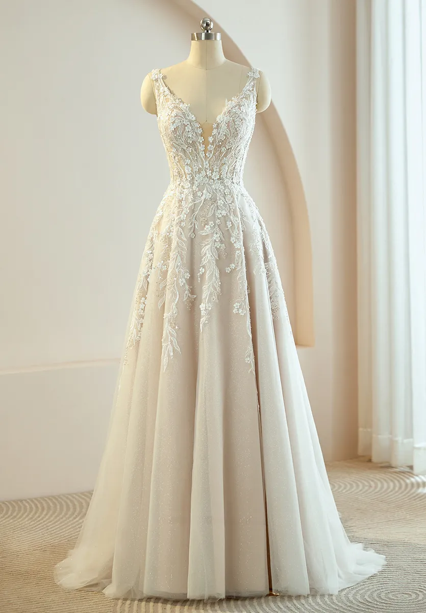 A-Linien-Brautkleid aus schimmerndem Tüll in Champagner mit tiefem V-Ausschnitt, floralen Spitzenapplikationen am Oberteil und weitem Rock mit Schleppe – romantischer Brautmode-Trend 2026 Zürich